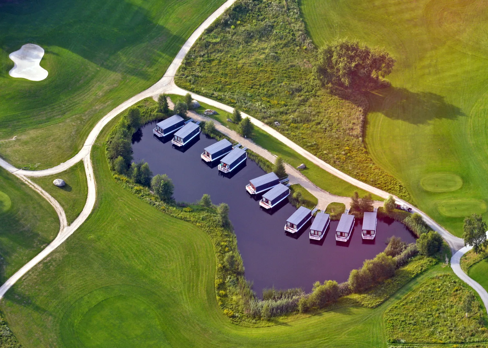 Vista aerea delle houseboat ormeggiate sul lago presso Ypsilon Golf Resort Liberec, circondate dal campo da golf