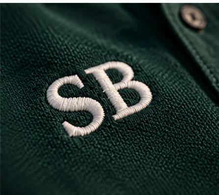 Close-up of a member’s initials embroidered in white on a dark green golf polo